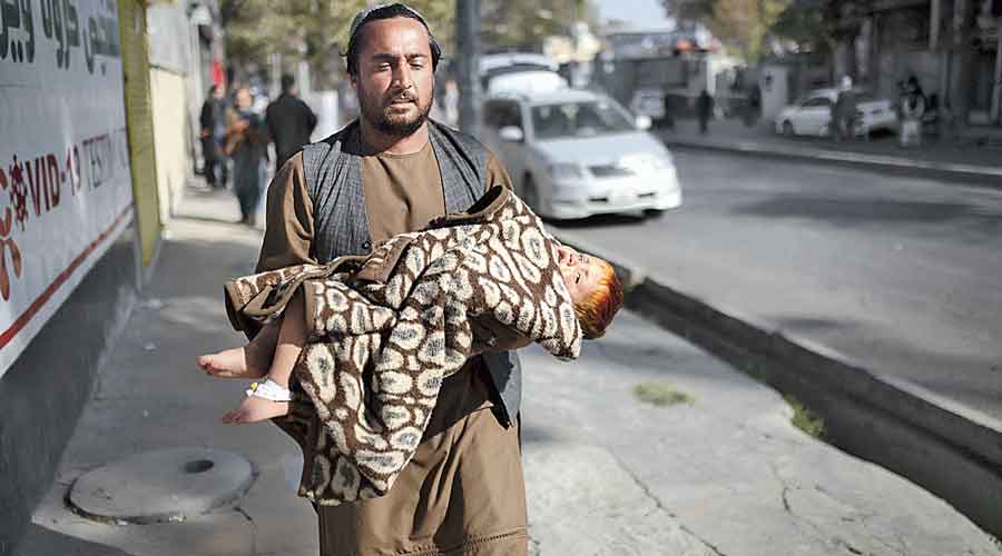 A man with a baby hurries away from the hospital after the attack in Kabul on Tuesday.