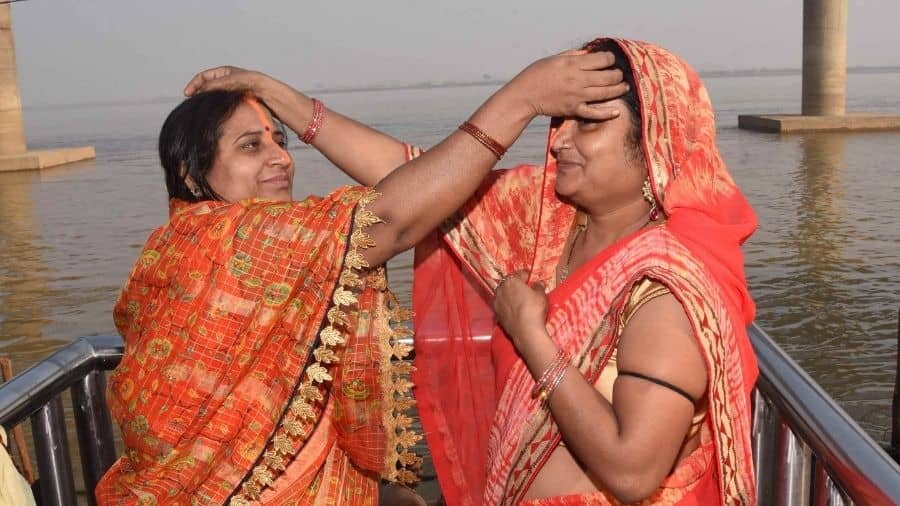 Hindu women apply vermillion to each other after taking bath in the holy Ganga River during the Kharna Puja of the Chhath celebrations, in Patna on Tuesday.