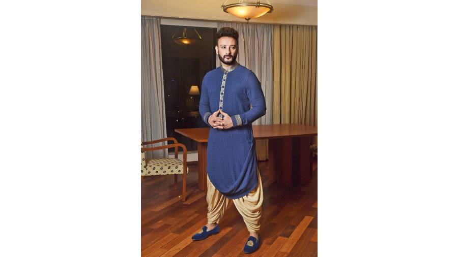 Shaheb exudes an elegant charm in this royal blue draped kurta detailed with antique gold brocade border teamed with golden cowl Patiala pants. “Every cut, fold, drape is made meticulously keeping in mind the expressive feel and tone of the fabric. It captures the essence of luxurious clothing. The symphony of drapes is elevated with intricate detailing and masterful craftsmanship,” said Jyotee.