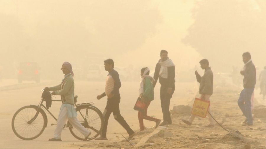 Commuters cross a road amid low visibility due to a thick layer of smog in Gurugram today.
