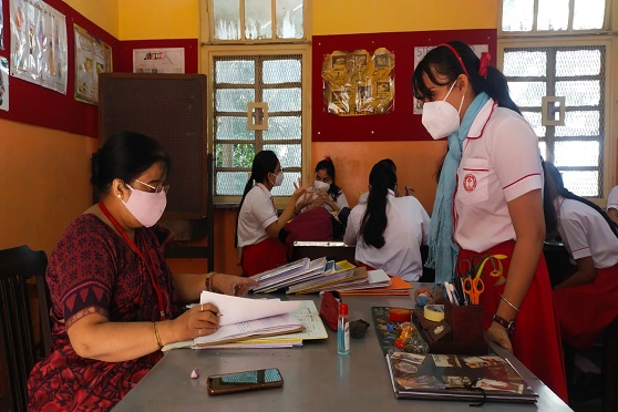 A student of Gokhale Memorial Girls' School gets her Home Science practical notebook signed by the teacher.  