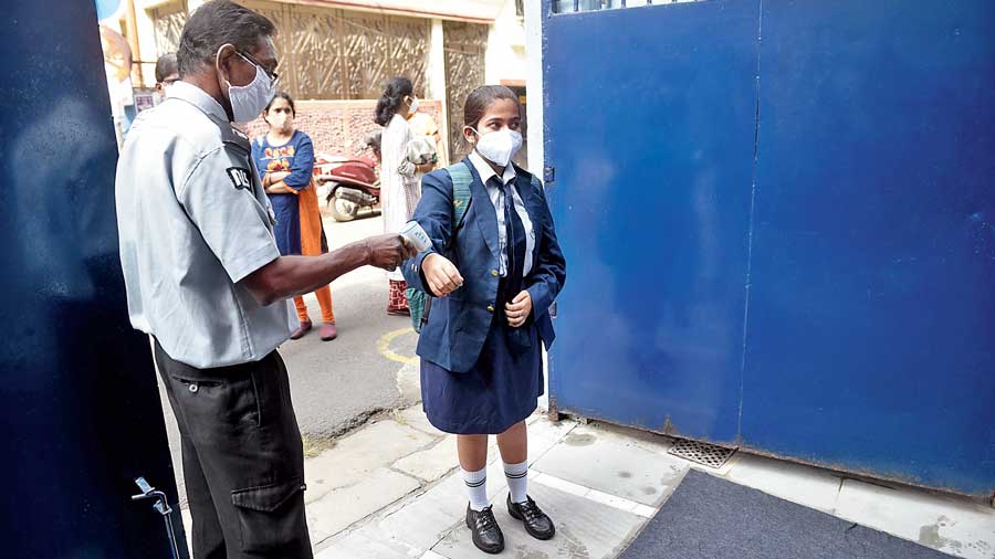 A student of South Point School gets her temperature checked before entering  the campus on Tuesday.