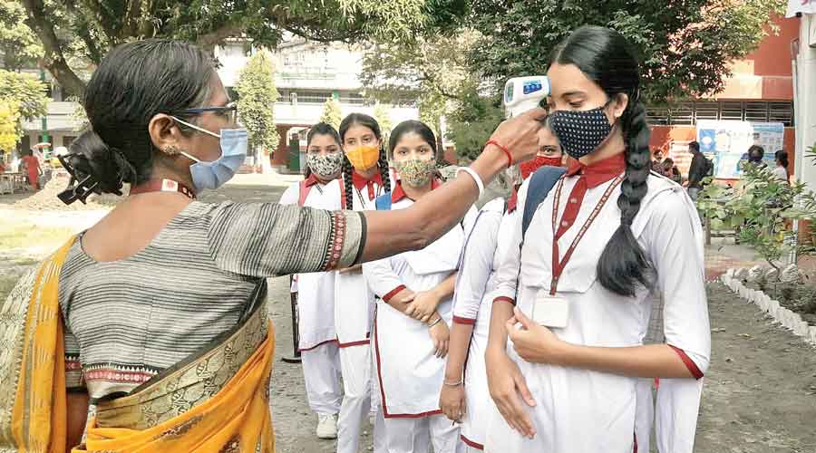Students being checked with a thermal gun at the entrance to a school in Siliguri on Tuesday.