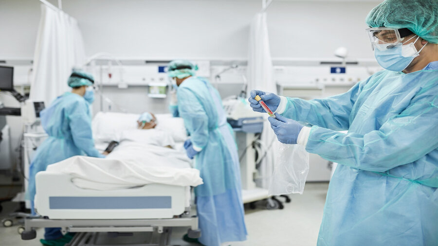 Doctors wearing protective workwear examine a COVID-19 patient in a ward in the United Kingdom