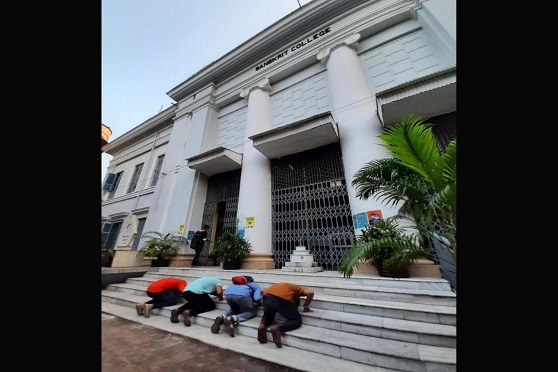 Four friends bow down on the staircase of The Sanskrit College and University before entering the campus. 