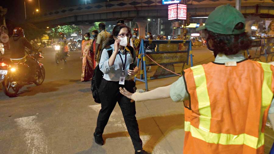 A civic volunteer and policemen manage pedestrian movement and traffic at the Chingrighata-EM Bypass crossing  on Thursday evening.