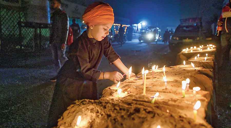 A child lights candles at the farmers’ protest site at the Singhu border on Friday.