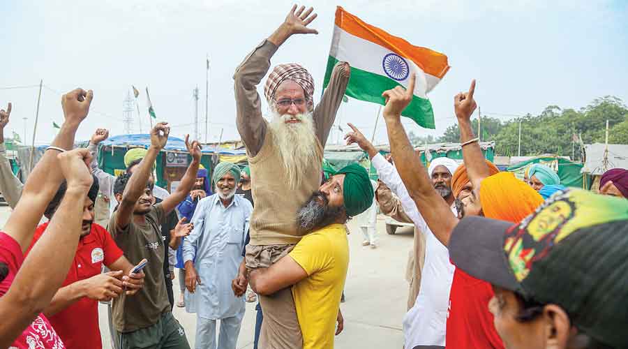 Farmers celebrate at the Tikri border in New Delhi  on Friday. 