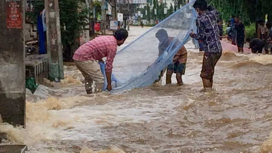 People trying to fish in a flooded street of Tirupati 