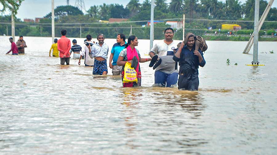 Residents wade through a flood-affected area in Nellore district of Andhra Pradesh, Saturday, Nov. 20, 2021.