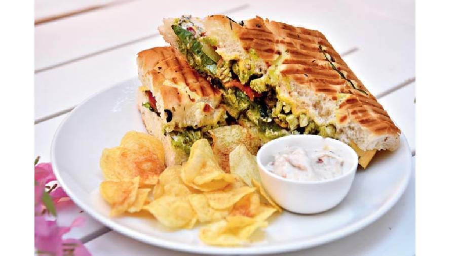 Caravan Cafe Special Pesto Sandwich: A light sandwich starring pesto and veggies that’s creamy and herby. Specially curated, it plays as well with its flavours as it does with its textures. It’s served with a side of chips and dip. Rs 230