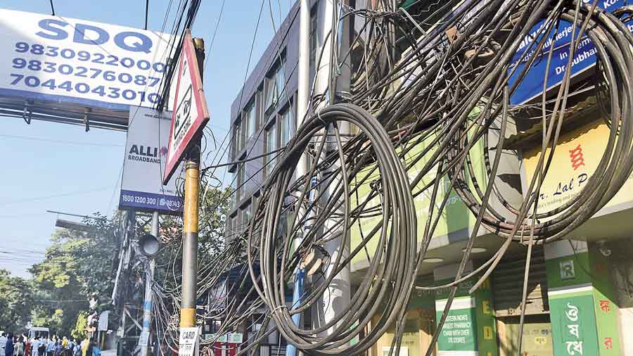 Overhead cables hang on poles on Harish Mukherjee Road.