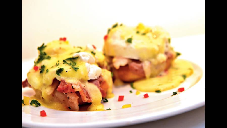 Eggs Benedict: Poached eggs served on a bed of crispy bacon on toasted English muffins, some creamy, light hollandaise sauce and freshly chopped coriander leaves is what a dream breakfast is made of! Rs 225