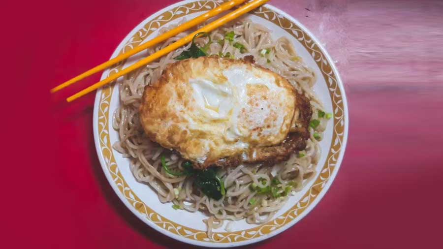 Noodles and veggies topped with a fried egg at Ah Leung
