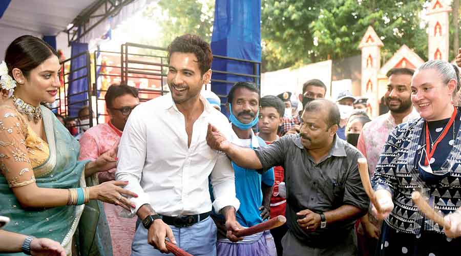 Five star puja: Actor Yash Dasgupta and Melinda Pavek, US consul general, play the dhamsa  as actress Nusrat Jahan looks on at 41 Pally in Haridevpur.