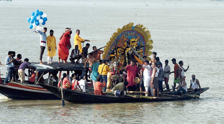 A Durga idol before immersion off Bagbazar ghat and (below) devotees click pictures of idols before immersion at Babughat. 