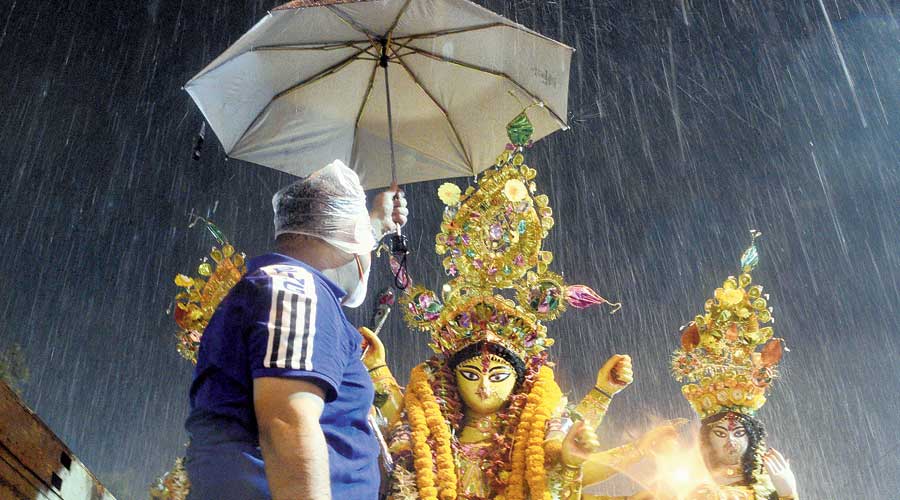 A man holds an umbrella over a Durga idol at Babughat on Friday. On Dashami, the showers were sharper, accompanied by lightning and rumblings of thunder.  A low-pressure area on the Bay of Bengal, advancing towards the Odisha and Andhra coasts, injected a lot of moisture into the atmosphere.  Coupled with the scorching heat accumulated over the day, the moisture formed thunderclouds which triggered the rain, said a Met official. The first half of Friday was hot and humid. The maximum temperature was 36.3 degrees, four notches above normal. The temperature was around 35 degrees in Kolkata at 1pm.  The RealFeel, however, was a staggering 43 degrees, mainly on account of high humidity.
