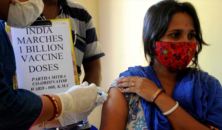 MILESTONE: A health worker inoculates a woman against Covid-19 at a clinic in Kolkata on Thursday, October 21, the day India completed administering 100 crore doses of Covid-19 vaccines
