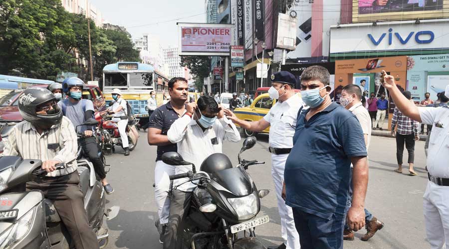 Policemen stop motorists and ask them to put on masks at Chandni Chowk on Tuesday afternoon. 