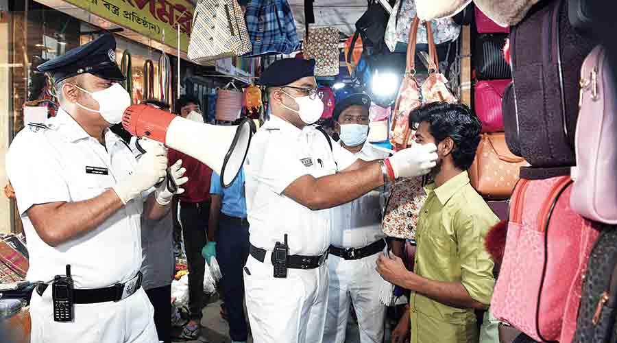 A policeman puts a mask on a hawker at the Gariahat market on Wednesday afternoon. 