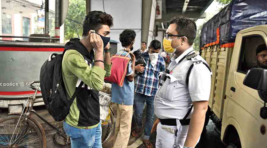 A police officer urges pedestrians on AJC Bose Road to wear masks on Thursday evening. 