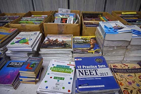 Competitive Examination resources including guidebooks and sample papers lay next to design books on applique thread work. 
