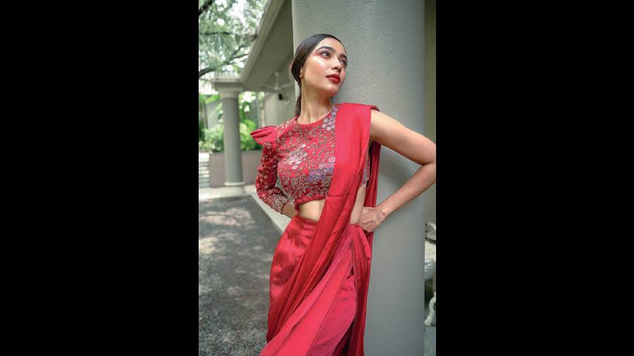 Diti looked gorgeous in this crimson red satin pre-draped sari, fitted like a dress with a sari drape and paired with an embroidered blouse. The style on the blouse sleeves adds drama to the look.