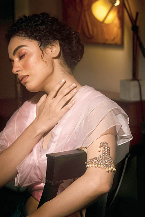 This hand accessory or baajuband is reimagined in this frame using a detachable polki kilangi accentuated with South Sea pearls from Sawansukha Jewellers. Usually worn on the turban and considered to be a male accessory piece, the kilangi, here glams up an organza outfit from Label Deepshika Agarwal.