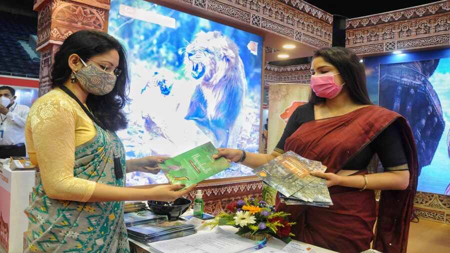 A travel representative hands over a tour brochure to a visitor at the fair.  