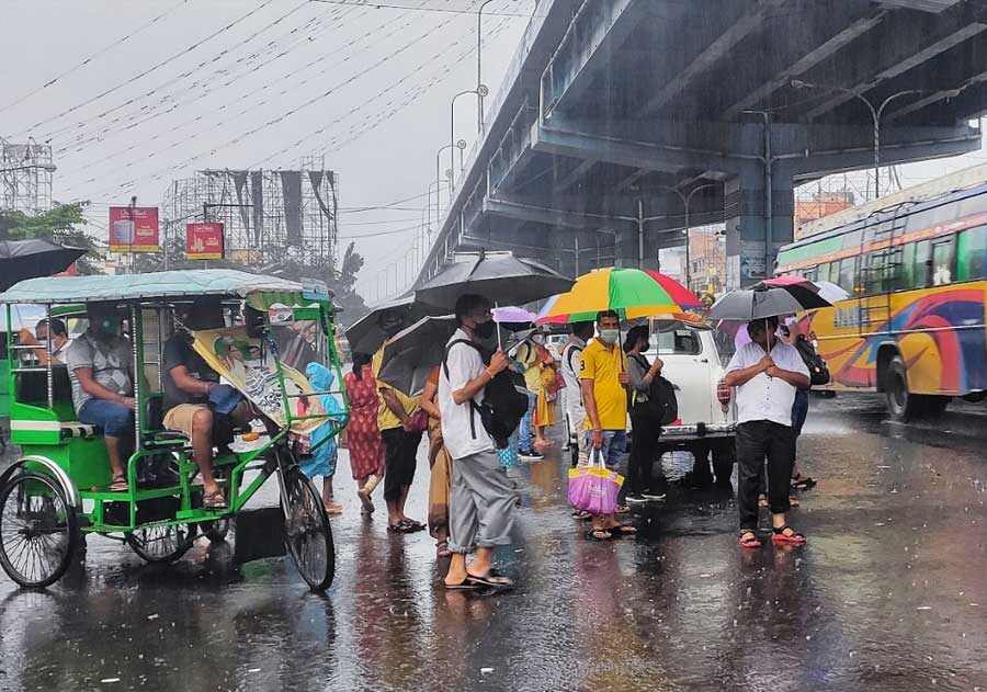 Commuters wait in the rain for transport on VIP Road on Tuesday morning. The city woke up to a gloomy sky and incessant rain on Tuesday