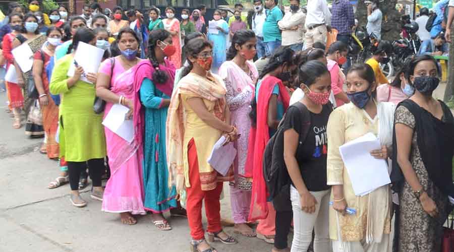 Aspirants stand in queue outside an exam centre to take the JPSC exam in Dhanbad on Sunday.