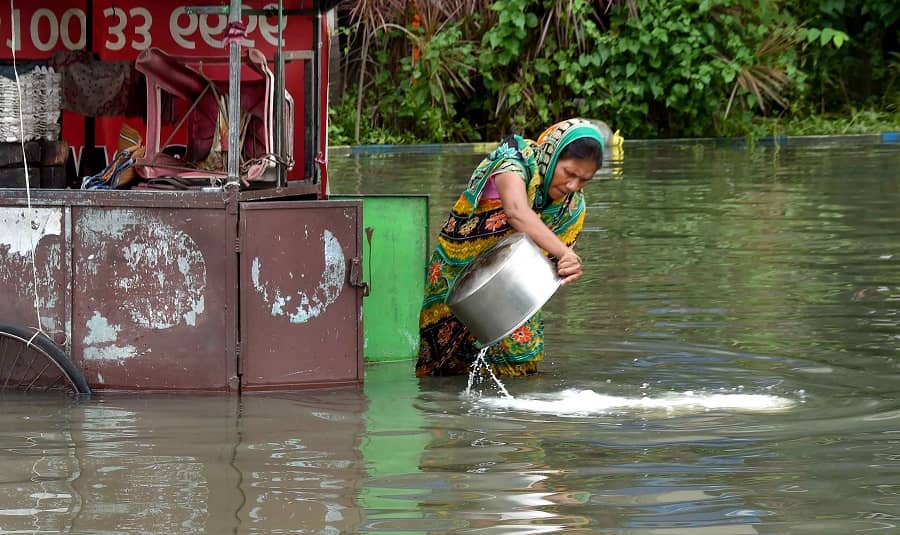 A woman throws milk on a waterlogged road from her tea stall after heavy rains in Kolkata on Tuesday.
