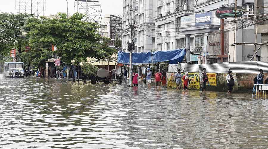 Pedestrians wade through a flooded road in Chinar Park around noon on Tuesday.