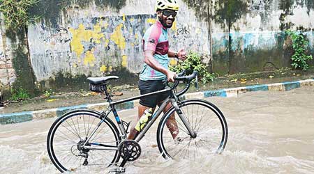 Pratap walks his cycle through a waterlogged area