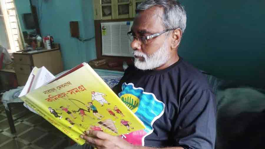 Cartoonist Debasish Deb, immersed in a Narayan Debnath book