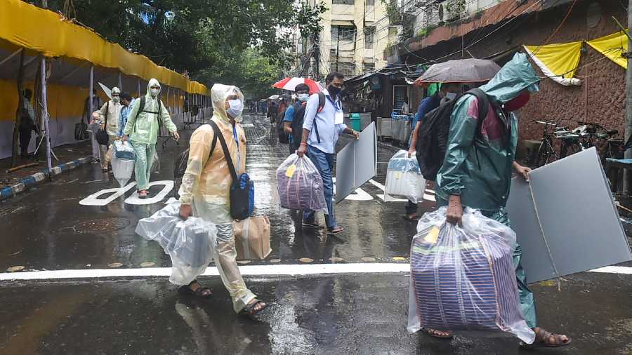 Polling officials carrying election materials amid rains in Bhowanipore 