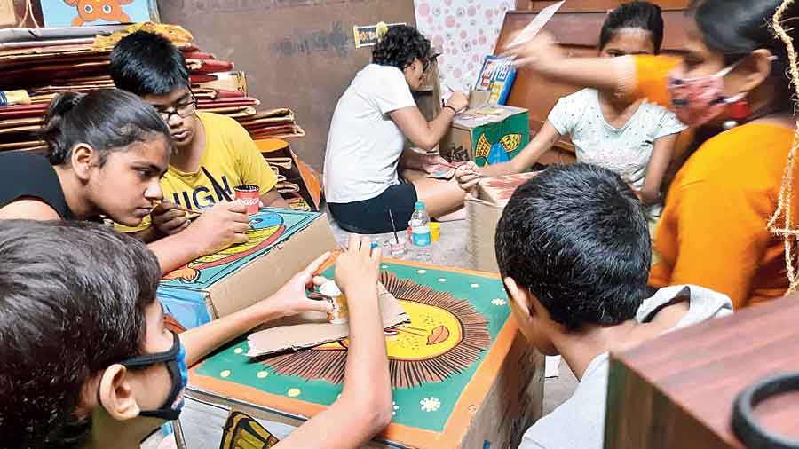 Children create patachitras on boxes at the SM Nagar Government Housing Estate Puja