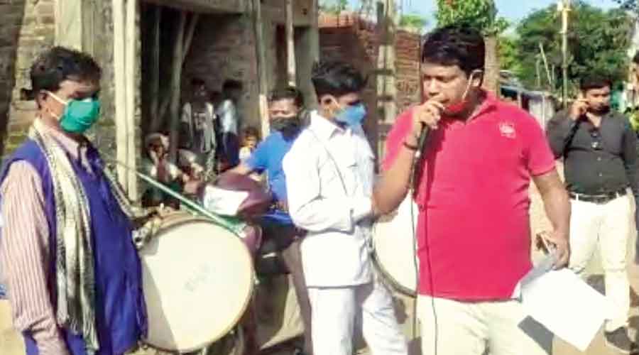 A civic official makes an announcement as a musical band performs in front of a beneficiary’s house in Lohardaga on Tuesday. 