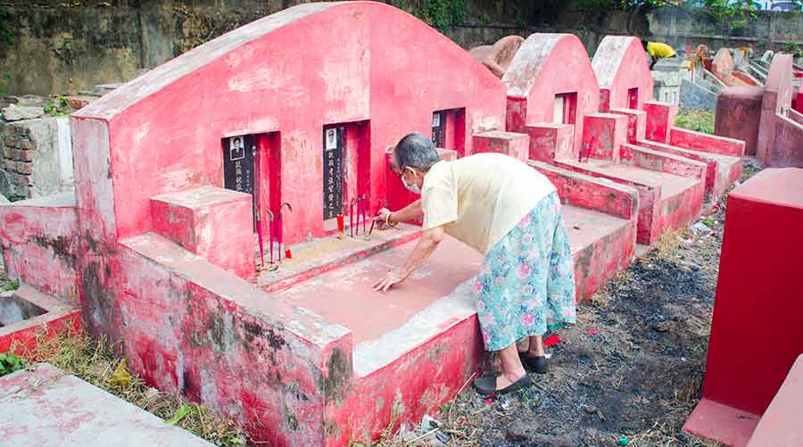 A woman places incense sticks on a tomb in Nam Soon Cemetery