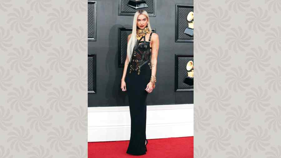 What do you do when you have the Grammy red carpet in Las Vegas? You opt for a bondage dress. Dua Lipa clearly knew how she is going to slay it on the red carpet as the Levitating hitmaker wore a Versace BDSM-inspired body-hugging outfit that she accessorised with chunky high-collar gold neckpieces and multiple bracelets. The platinum blonde hair accentuated the edgy factor.