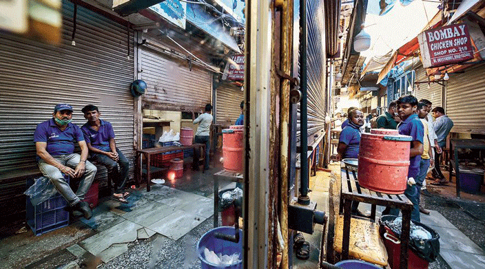Workers sit outside closed meat shops at the INA Market in New Delhi.