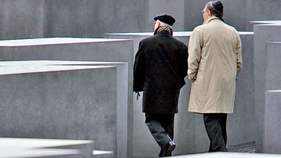 Two visitors walk among the approximately 2,700 stellae of the Holocaust Memorial in Berlin, Germany