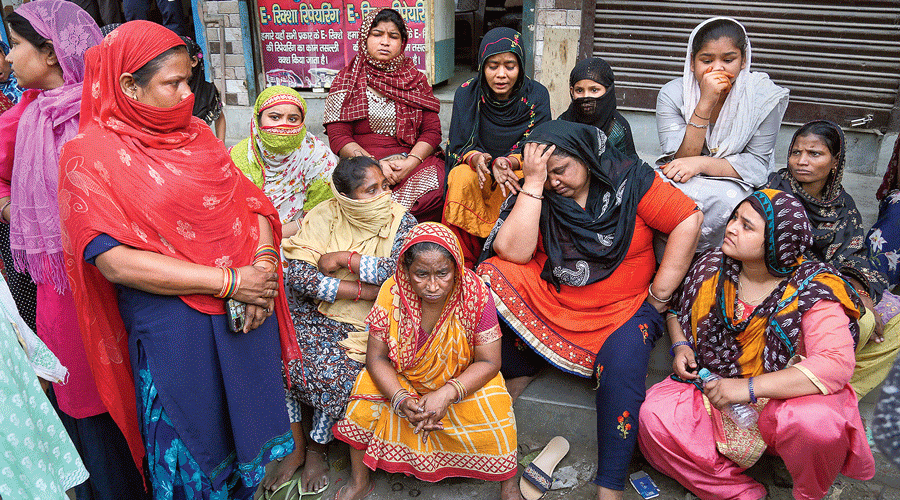 Relatives of some of  those who had been detained and other residents wait outside Jahangirpuri  police station in Delhi on Monday.
