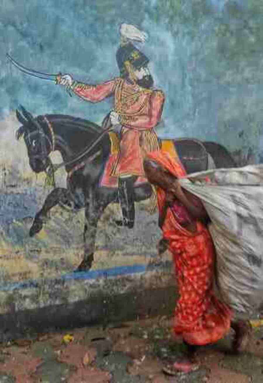 An underprivileged elderly passes a mural on a Kolkata street on Wednesday. 