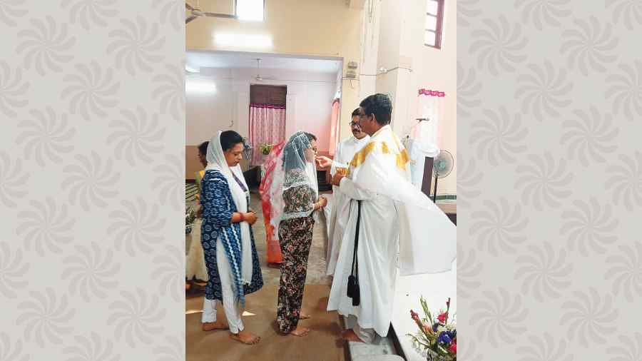 Devotees observe Eucharist by accepting portions of bread and wine after Easter Service at Emmanuel Church in Kestopur.