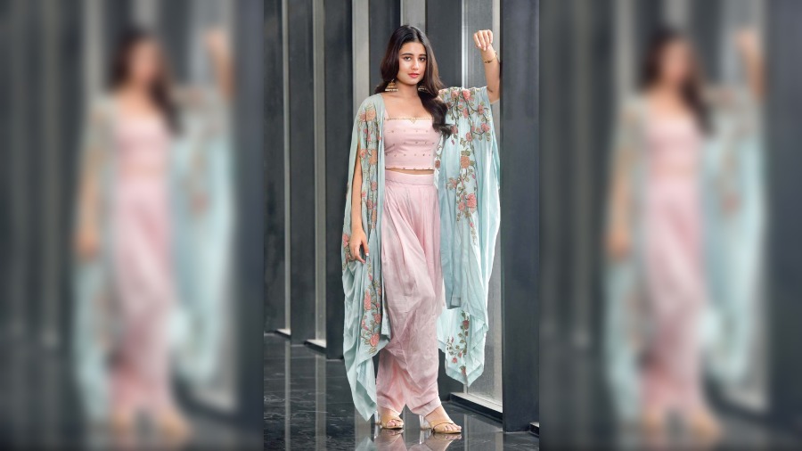 Keep your summer wedding bachelorette look easy-breezy to be carefree in the fun mood with your girl gang. The silk and cotton soothing pink embellished top is paired with cowl pants and a sky blue cape detailed with zardosi-style floral work with thread and beads. 
