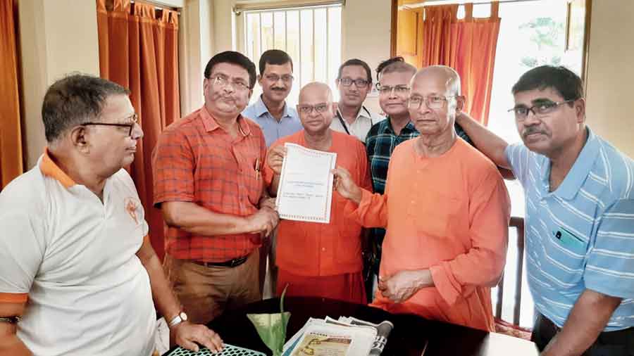 Former students hand over the amount to Swami Ekavratananda, secretary of the Ramakrishna Mission Calcutta Students’ Home in Belgharia, on Sunday
