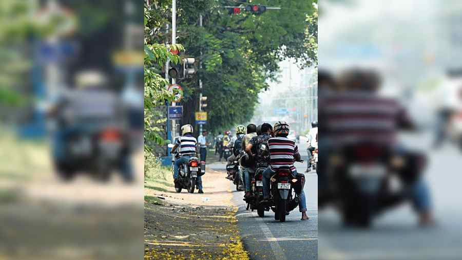Motorcyclists wait in the shade at a traffic signal on Kidderpore Road on Tuesday morning. 