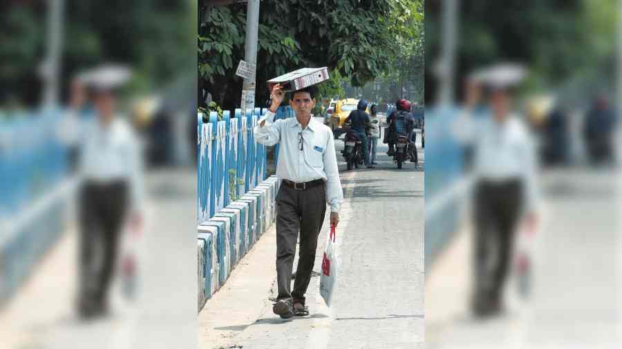 A pedestrian uses a file cover to shield himself from the sun on Wednesday afternoon. 