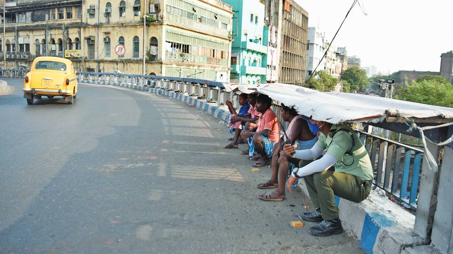 Pedestrians and a civic volunteer take shelter from the sun on the Brabourne Road flyover on Thursday afternoon.  